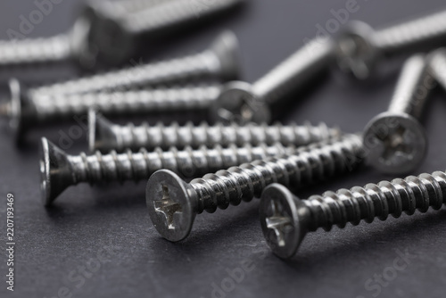 Tapping screws made of steel, metal screw, iron screw, chrome screw on dark background