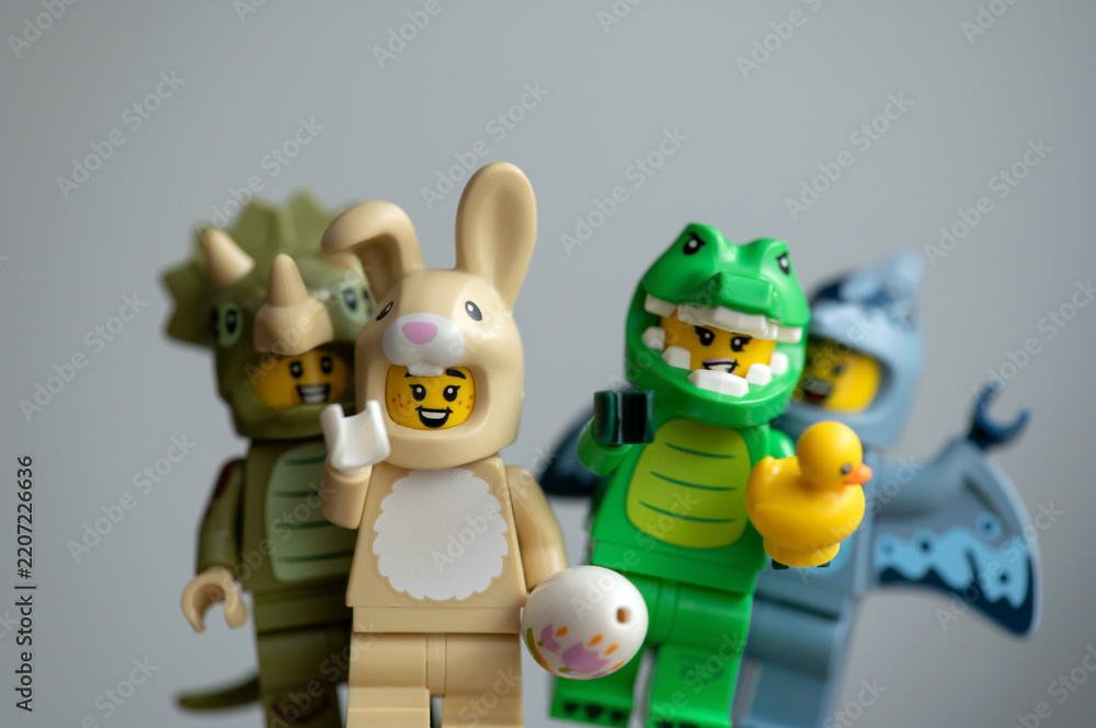 Obraz premium Lego minifigures animal-costume: a fun group featuring a crocodile, rabbit, pterodactyl, and triceratops on a gray background.