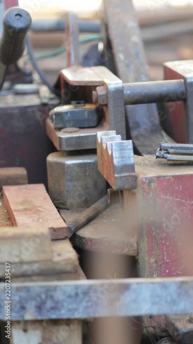 Vertical video of worker cutting steel rebar with a machine