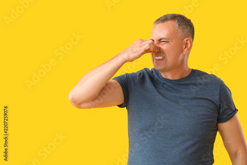 Fotografie Bad smell and disgust concept, man pinching nose to block foul odor with facial