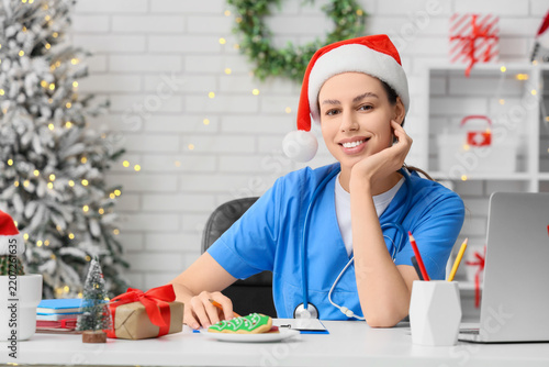 Christmas healthcare and holiday medical shift, nurse wearing Santa hat worki...