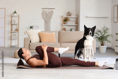 Home workout and wellness, woman stretching on yoga mat with border collie do...