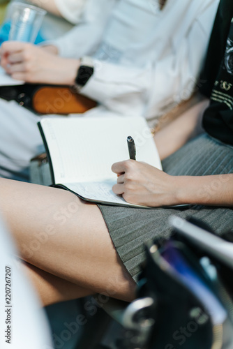 Closeup Of Woman in Short Skirt Writing Notes In Notebook During Business Meeting