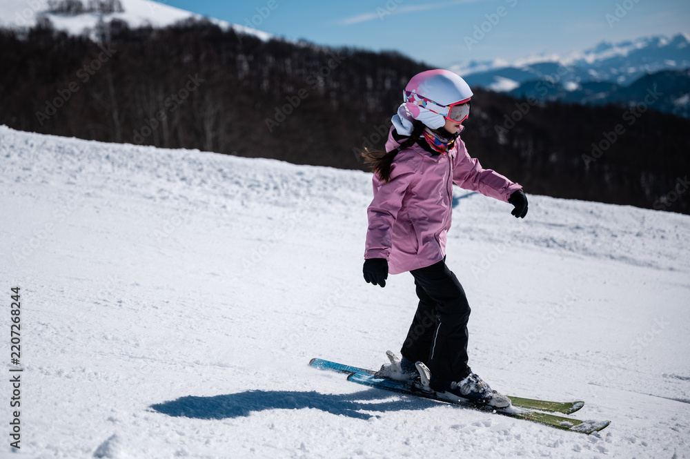 Obraz premium Little girl learning skiing on a sunny mountain slope