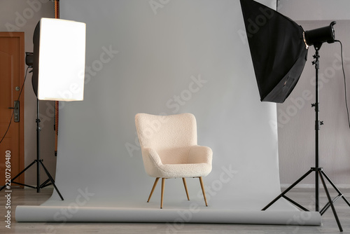 Interior design and furniture photography, modern cream armchair in a professional studio setup with lighting equipment and grey backdrop