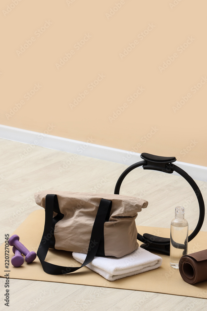 Obraz premium Fitness and wellness routine, gym bag with pilates ring and dumbbells on yoga mat for healthy lifestyle and active living in home workout environment