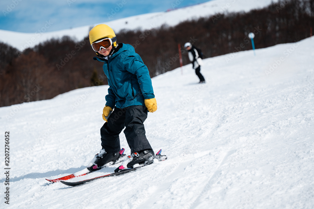 Fototapeta premium Young child learning skiing on snowy mountain slope
