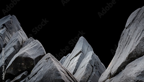 close up of weathered grey rock formations possibly mountain peaks with a sharp irregular outline against a stark black void above rugged natural texture