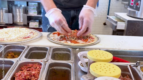 Chef Adding Fresh Toppings on Pizza in Commercial Kitchen