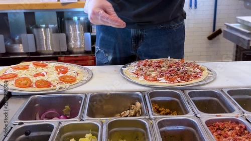 Chef Adding Fresh Toppings on Pizza in Commercial Kitchen