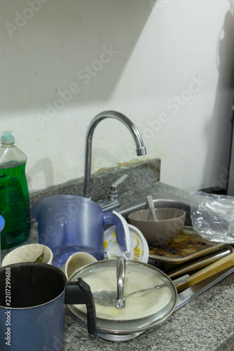 Pile of dirty unwashed dishes filling kitchen sink