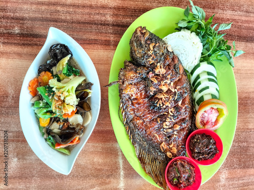 Obraz na plátně An Indonesian meal featuring grilled fish served with fresh vegetables, sambal, and a side dish of cap chye