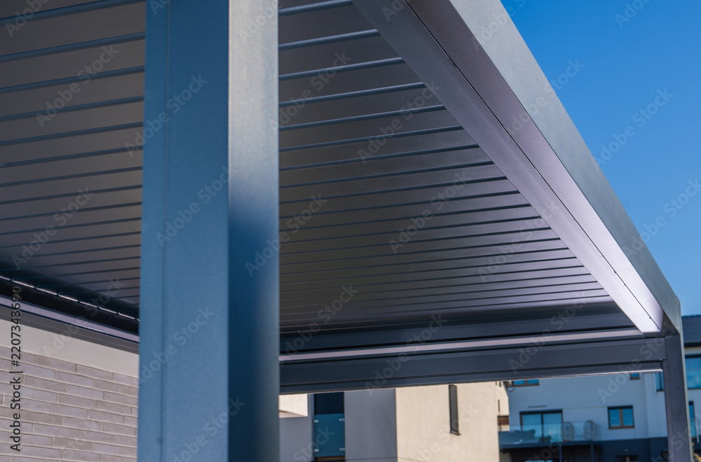 Obraz premium Modern metal pergola with a louvered roof against a blue sky