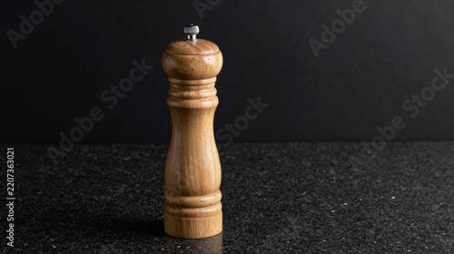 Wooden pepper mill grinder on a dark granite countertop