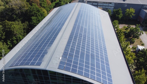 Solar panels on a building roof top with trees.