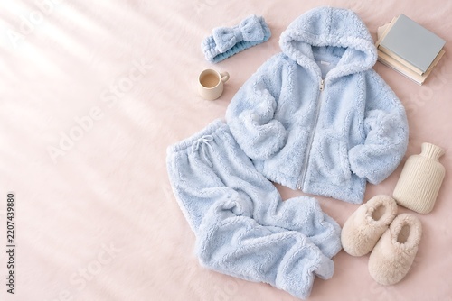 冬のあったかルームウェアとリラックスアイテムのフラットレイ｜パーカー、パンツ、スリッパ、ヘアバンド、マグカップ、本、湯たんぽ