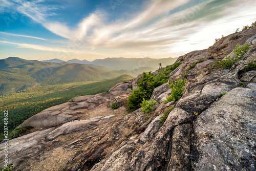 Rocky cliff overlook above a green valley under a blue sky