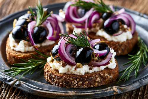 Elegant Canapes with Cream Cheese, Olives, and Red Onion on Rustic Plate