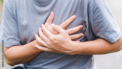 Unrecognizable male grabbing his chest experiencing acute left side chest pain. Depicting symptoms of myocardial infarction, severe heartburn, cardiac arrest, and critical health issues.
