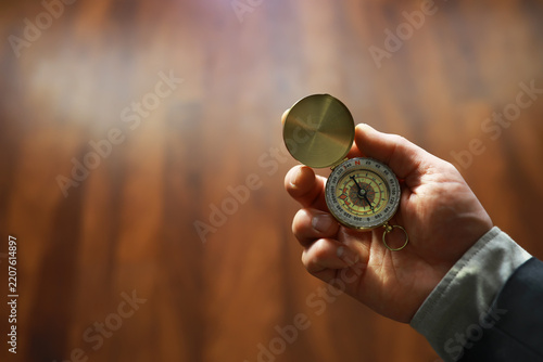 man in suit holding golden compass on gray background
