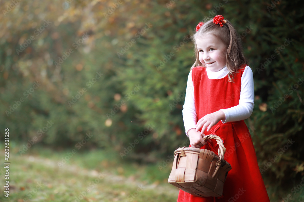 Obraz premium A little girl in a red hat and dresses is walking in the park. Cosplay for the fairytale hero 