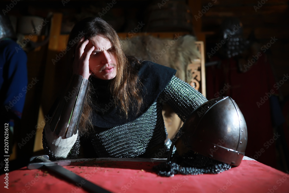 Obraz premium A mighty hero with long hair in chain mail armor in an ancient hall. Medieval warrior in the knight's chambers.