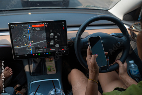 Woman drive EV car use smartphone in city with GPS navigator