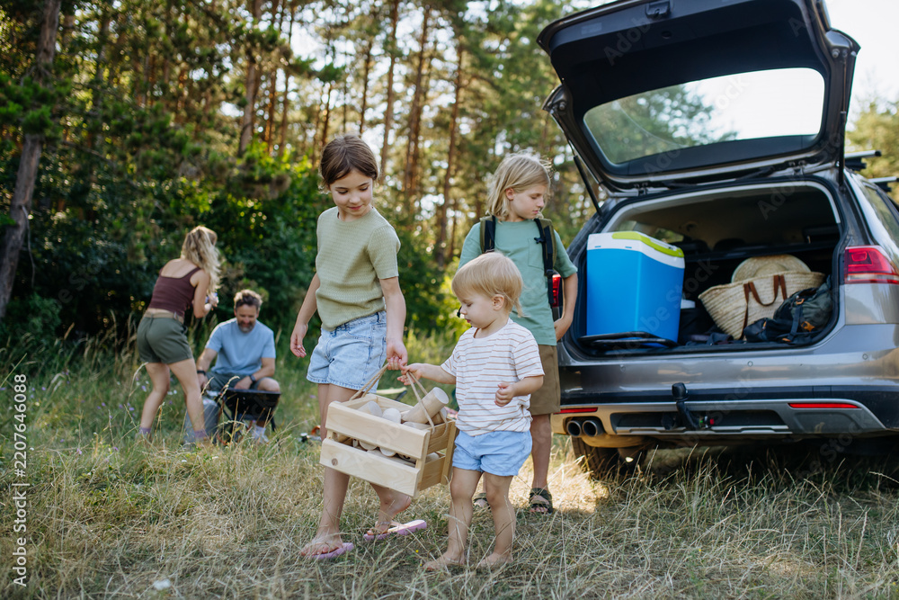 Obraz premium Family unloading luggage from car and setting up a campsite.