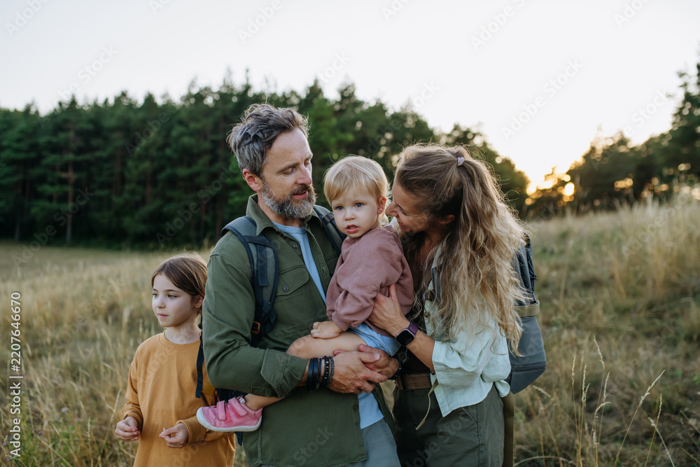 Obraz premium Family hiking together through countryside during summer camping trip.