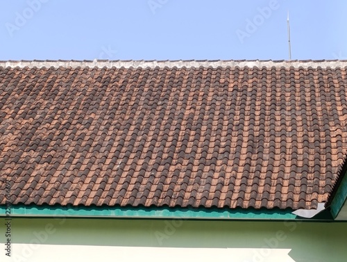 Clay roof tiles form an even pattern.  A bright blue sky sits above.