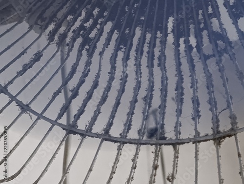 Dust accumulation covers a metal fan grill.  Thin wires are heavily coated.