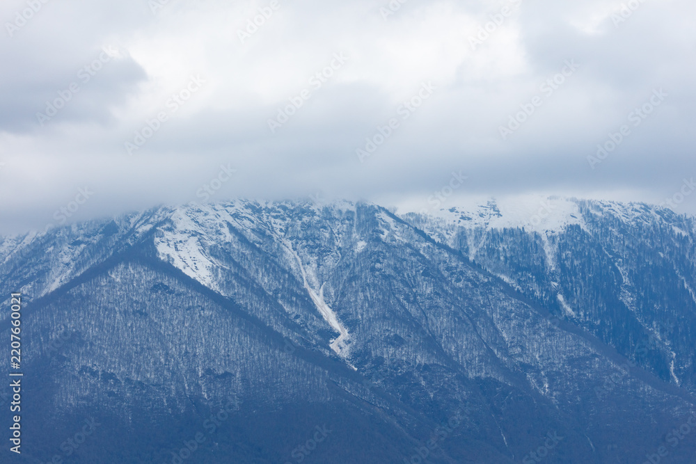 Obraz premium Snow-capped mountains rise beneath a cloudy sky