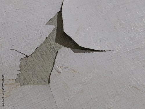 Cracked white paint reveals gray surface. Surface is textured and worn.
