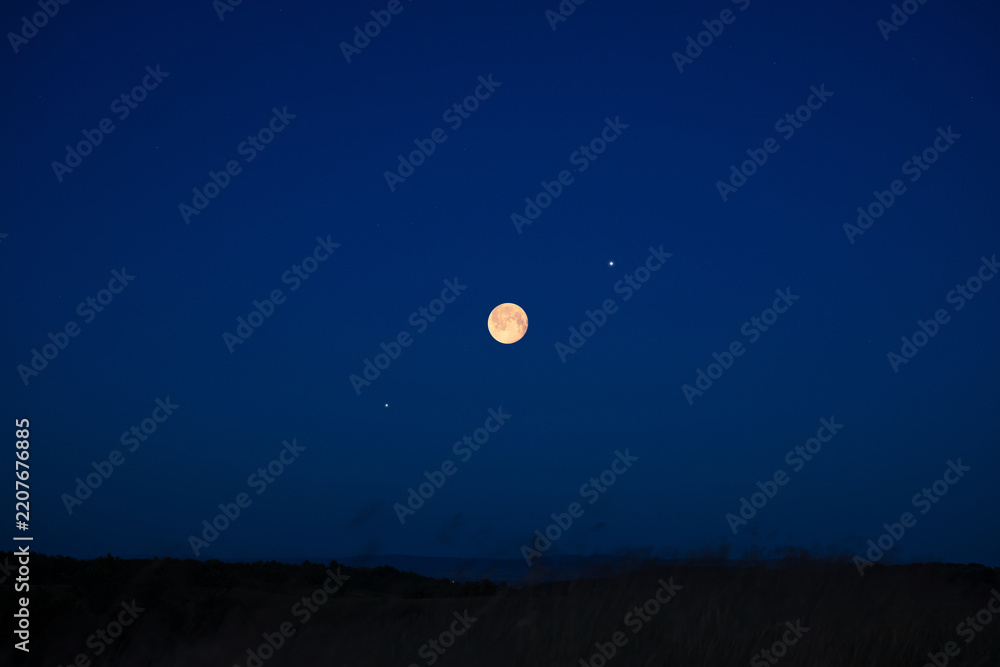 Fototapeta premium Full Moon on a twilight sky with landscape silhouettes.