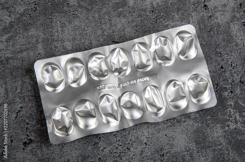 Used and empty aluminum blister packs from tablets and medications. Medical waste. Concept of empty packaging on a gray background.
