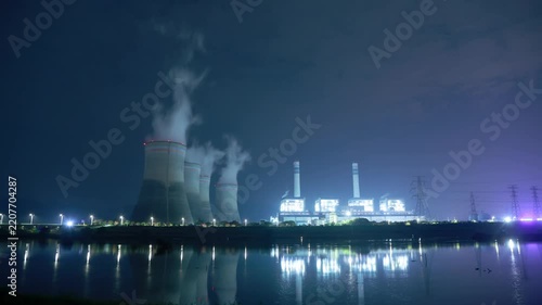 night view of power plant cooling towers and lights reflection on water surface