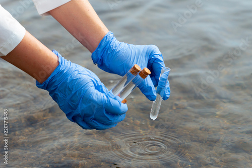 Fotografie scientist gloved hands collecting water sample test tubes lake river surface mic