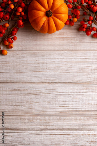 Orange Pumpkin and Wild Red Berries on a Rustic Weathered Wooden Board