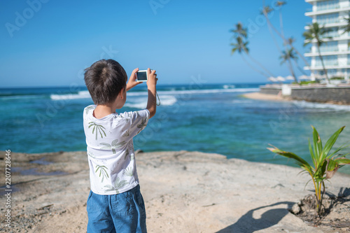 Child capturing memories on smartphone at tropical island getaway