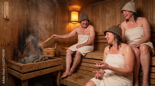 Group of friends laughing while relaxing in a traditional wooden sauna