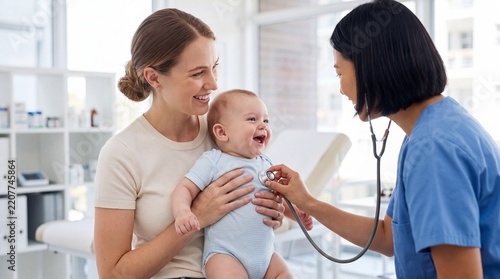 Pediatrician examining smiling baby with stethoscope while mother holds child in bright modern medical clinic