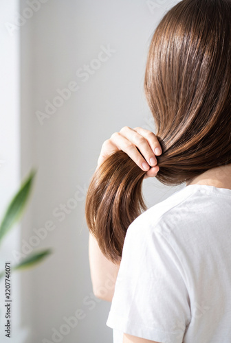 Woman holding long hair while looking away in a bright room  