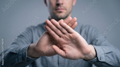 Man showing stop gesture with hands held up against gray background