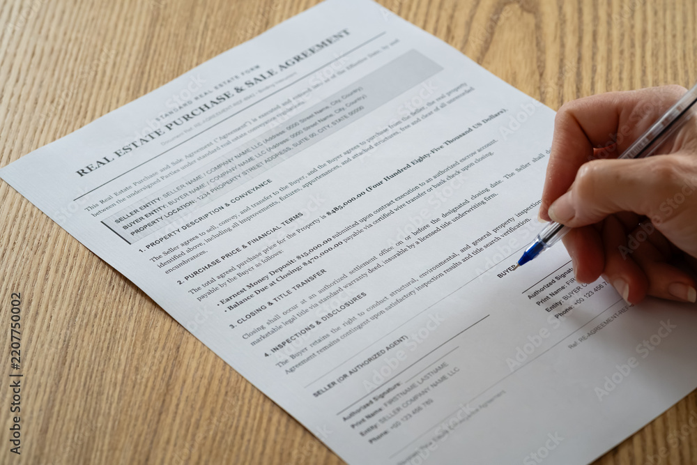 Fototapeta premium Person signing real estate purchase and sale agreement contract on wooden desk close up 