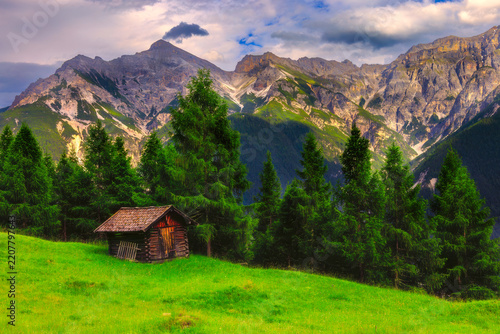 Alpine mountain cabin beneath dramatic peaks