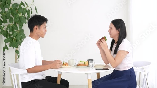 Japanese man and woman eating sandwiches face to face at a round table on a date