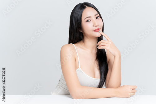 Happy young Asian woman finger touching on mouth with glowing face natural makeup and healthy black hair isolated on white background, for advertising about lipstick, skincare and cosmetics concept.