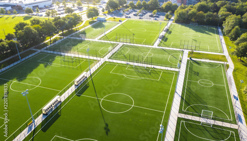 Aerial view of modern outdoor soccer complex with multiple green turf fields and white markings during sunny day, sports facility for team training and recreation