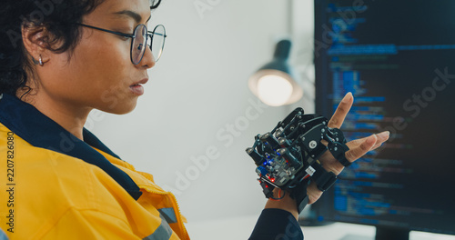 Close-up young Black female engineer coding AI robot arm in modern laboratory. Robotics, artificial intelligence, technology, stem, future, innovation, diversity, automation, machine learning concept.