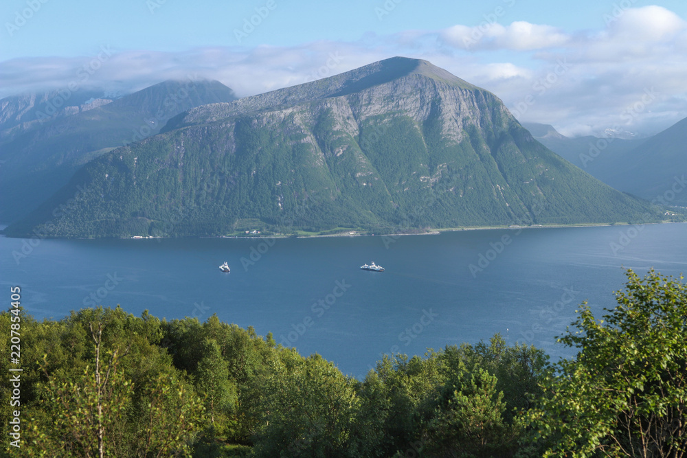Obraz premium Beautiful norwegian fjord landscape with ferries operating at Solavagen pier. Storfjorden fjord with steep mountain slopes in the sunnmore region of Norway.